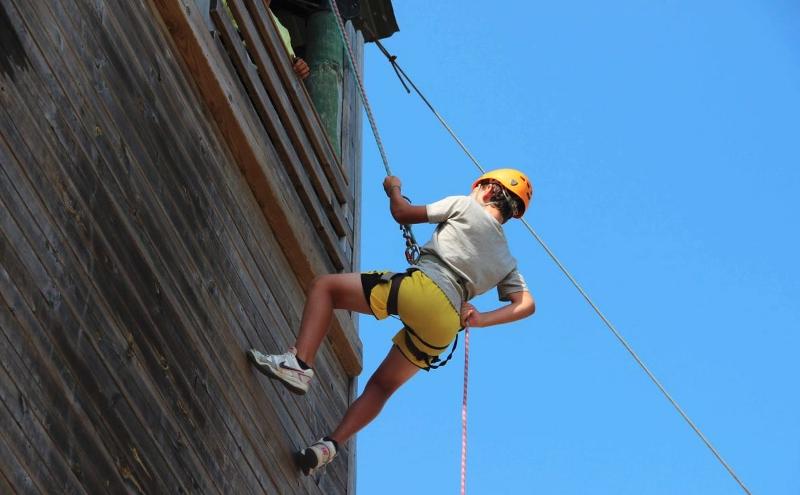 Un ragazzo del soggiorno linguistico Malta si sta calando con una corda da in cima ad un muro