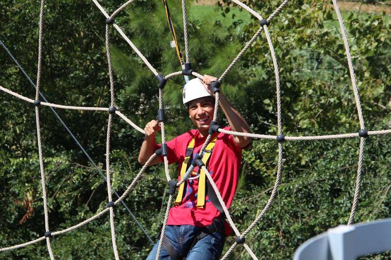 Un bambino del campo estivo di inglese in Italia indossa un elmetto e si sta arrampicando su una rete 