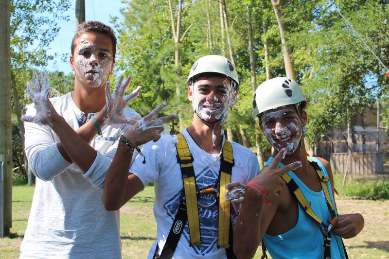 Tre ragazzi del campus estivo si divertono con la panna montata dopo aver fatto arrampicata