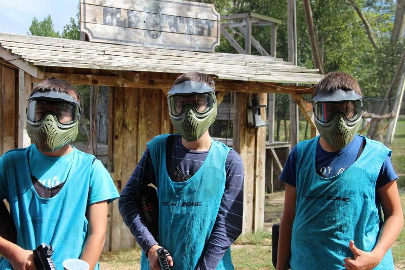 Tre ragazzi con la maschera protettiva si preparano a giocare a paintball al campo avventura