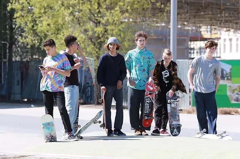  Un gruppo di ragazzi con la tavola in mano si allenano sullo skateboard a imparare nuovi trick