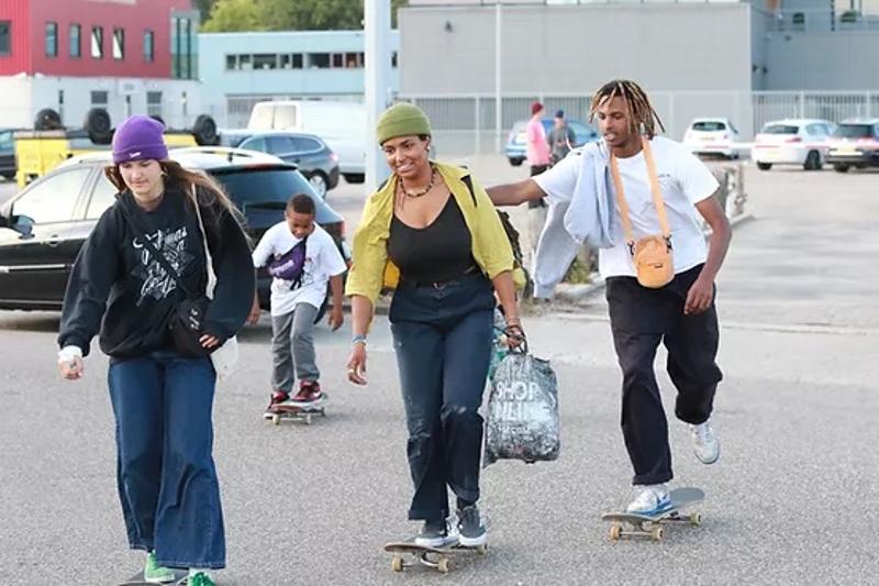 Due ragazze e un ragazzo del campo estivo skateboard cavalcano la tavola insieme per strada