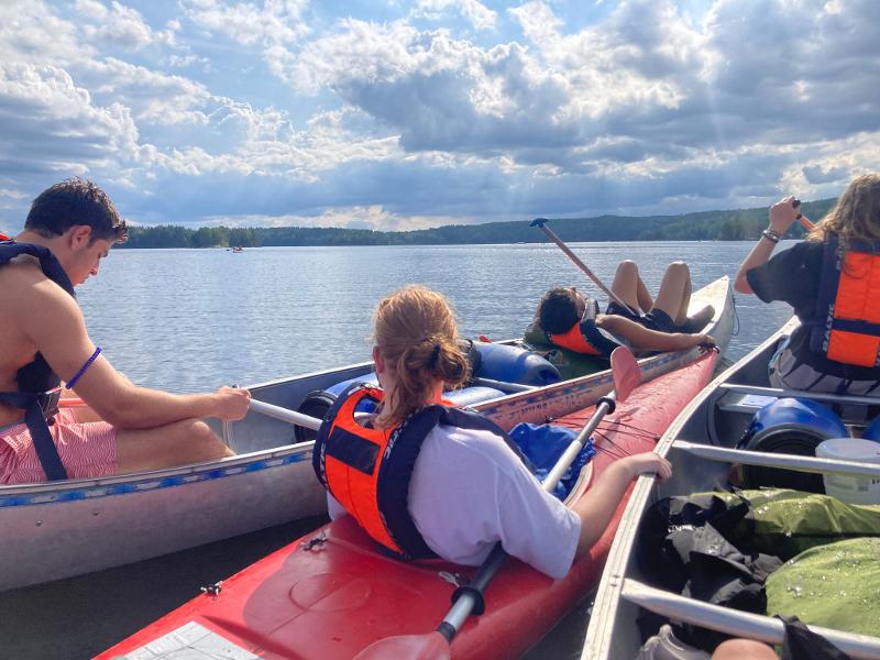 Dei ragazzi fanno canoa al campo avventura in Svezia, il cielo è chiaro e i ragazzi si godono la bella giornata in canoa
