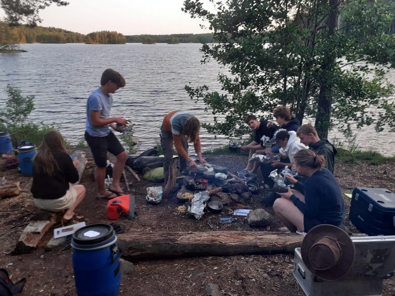 Ragazzi mangiano all'aperto con vista sull'acqua durante il campo avventura in Svezia