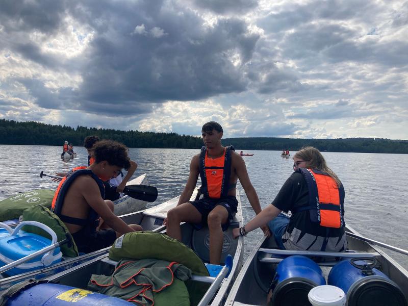 Ragazzi mantengono le canoe una vicino all'altra tenendole con le mani al campo avventura in Svezia