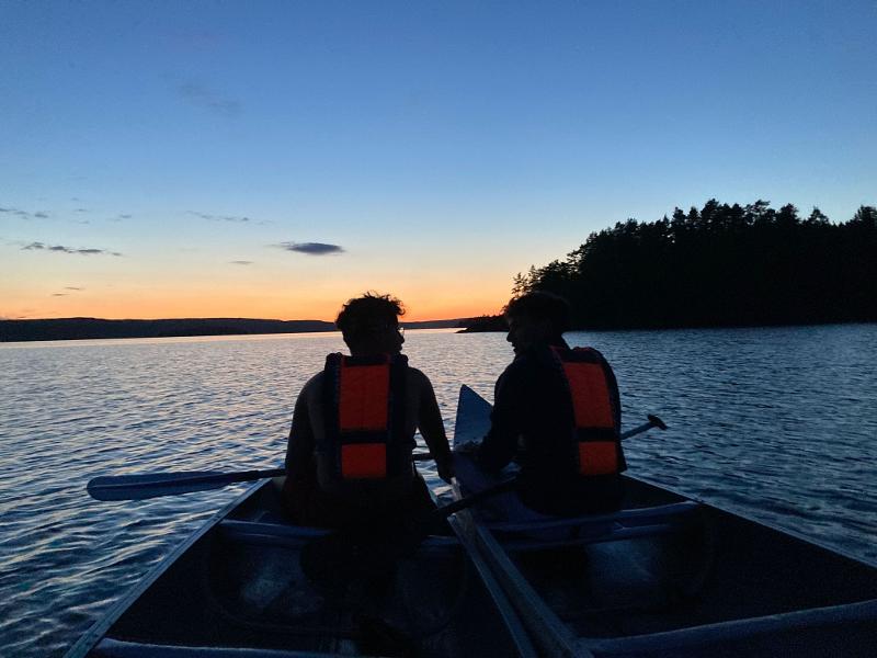 Ragazzi che chiacchierano durante una escursione in canoa al tramonto al campo avventura internazionale in Svezia 