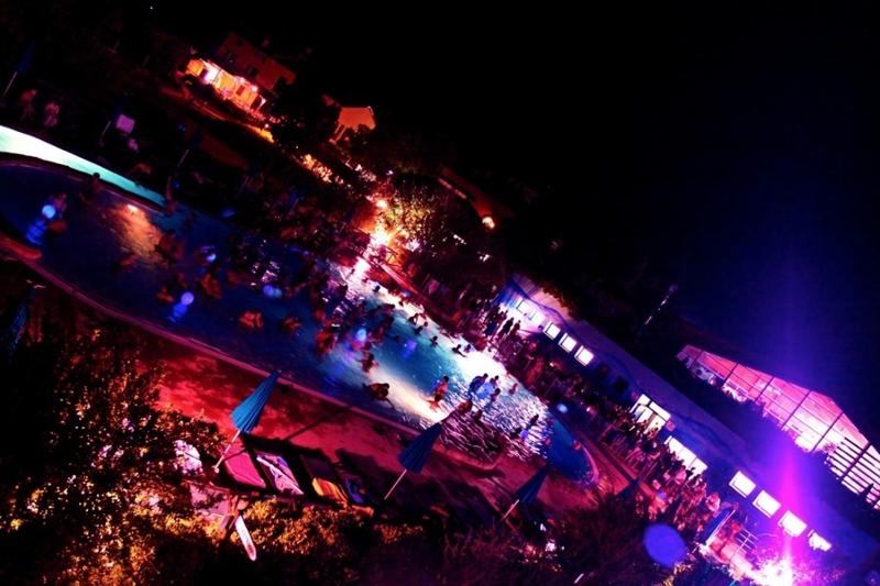 Si vede la piscina del campo vacanze per ragazzi Italia illuminata di notte e in piena festa