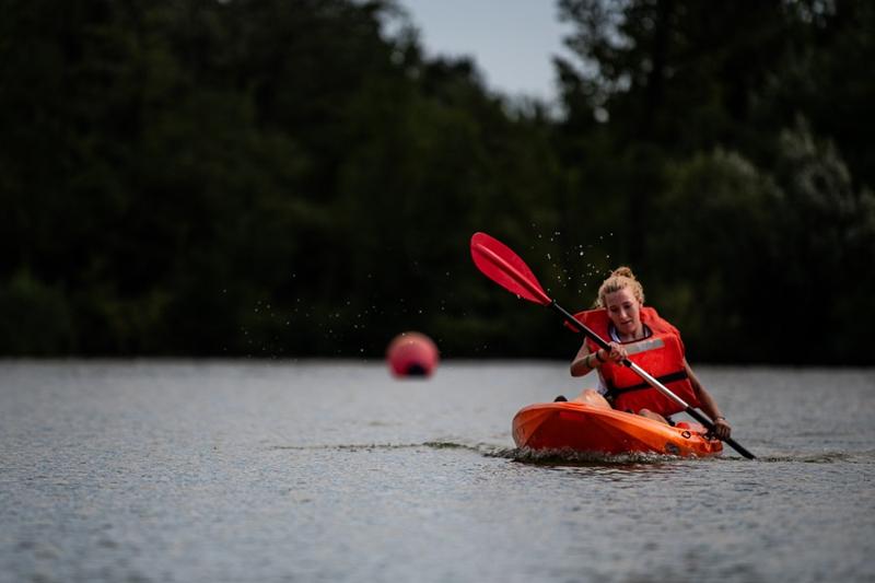 Al campo estivo all'estero una ragazza sta remando sul kayak e indossa una veste da salvataggio rossa