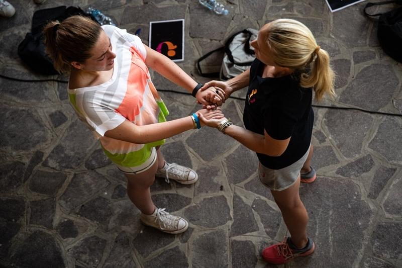 Due ragazze si tengono per mano e respirano al campo estivo motivazionale