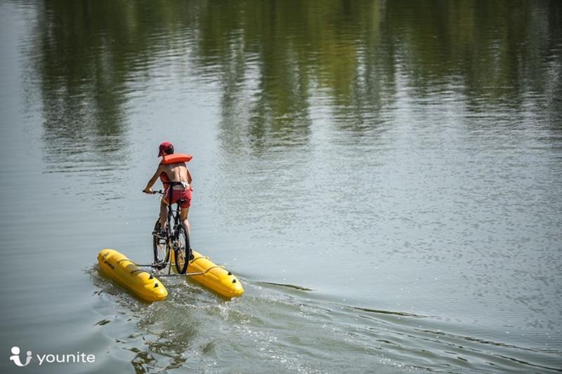 Un ragazzo pedala sulla bici d'acqua con addosso un giubbotto di salvataggio al campo estivo inglese Toscana