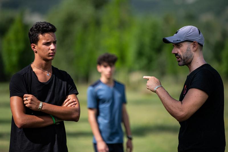 Al campo estivo motivazionale un coach con il cappellino da indicazioni a un ragazzo 