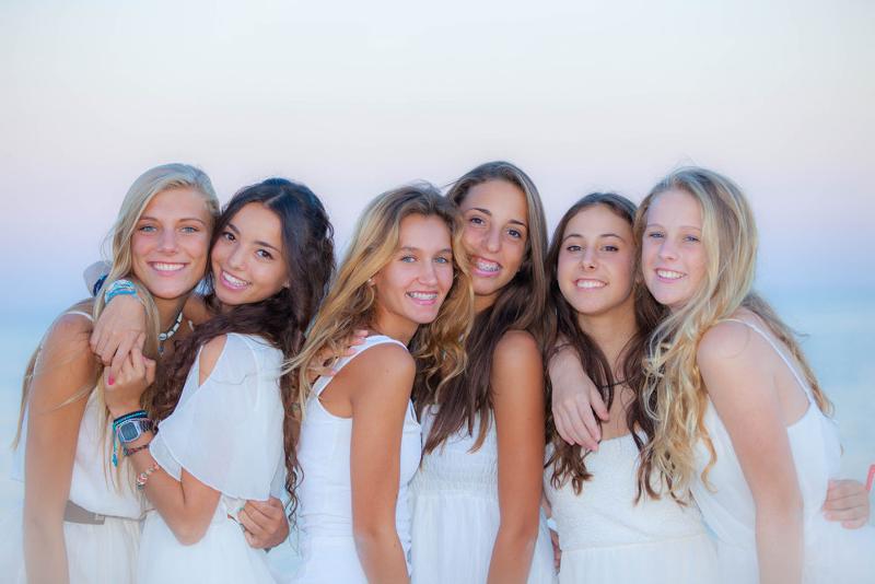 Presso i viaggi per ragazzi soli, sei ragazze vestite di bianco si abbracciano come vere amiche