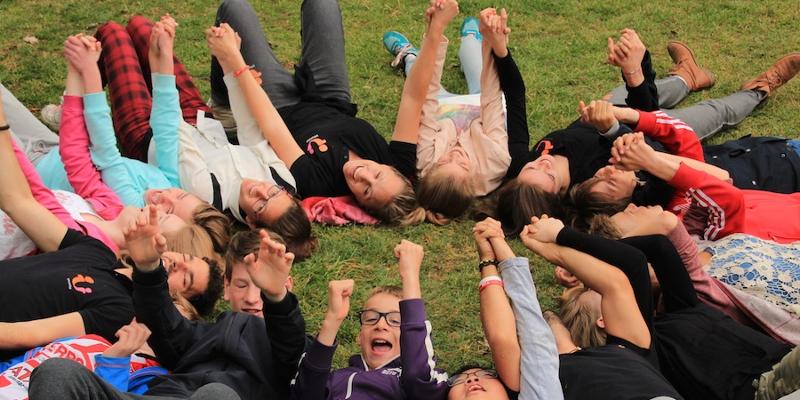 Il gruppo di ragazzi del soggiorno linguistico Inghilterra sono sdraiati in cerchio su un prato verde