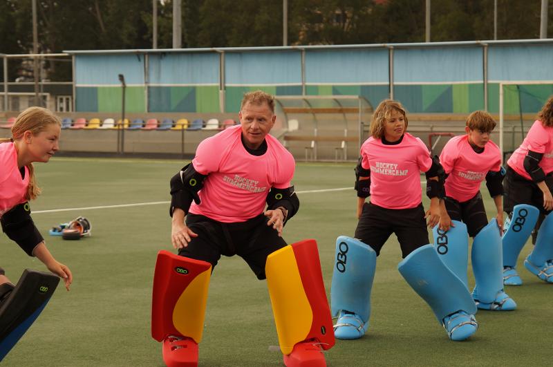 Al campo estivo internazionale di Hockey a Rotterdam i ragazzi e l'istruttore praticano sport in campo con le protezioni per le gambe