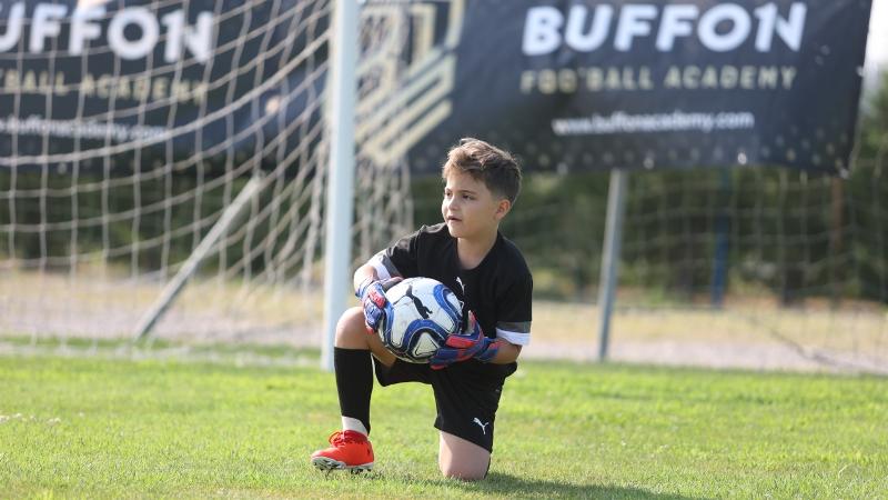 Un piccolo aspirante portiere del campus estivo calcio si rialza a seguito di una parata