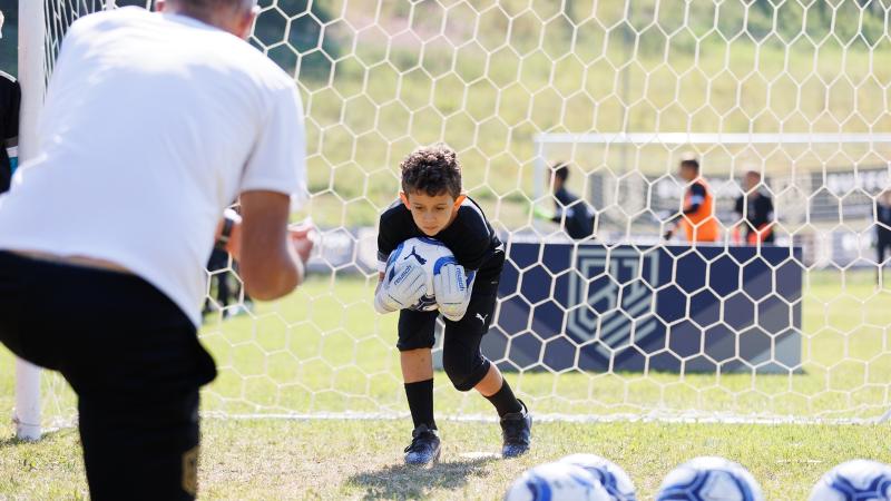 Un partecipante del campus estivo calcio viene allenato sulle parate in bloccaggio
