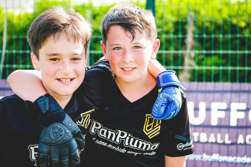 Al campo estivo bambini due piccoli portieri si abbracciano e sorridono