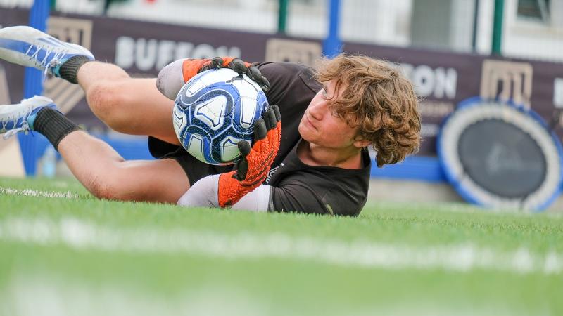 Un ragazzo partecipante al campus estivo calcio si tuffa in parata riuscendo a bloccare il pallone