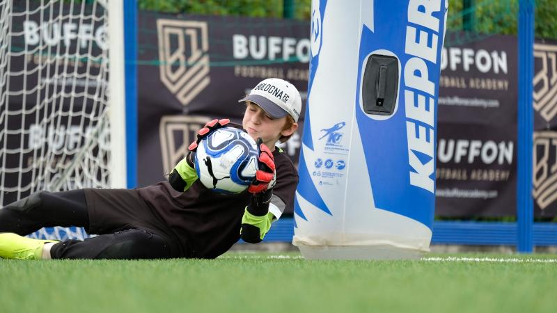 Un partecipante al campus estivo calcio si tuffa con successo in un'acrobatica parata