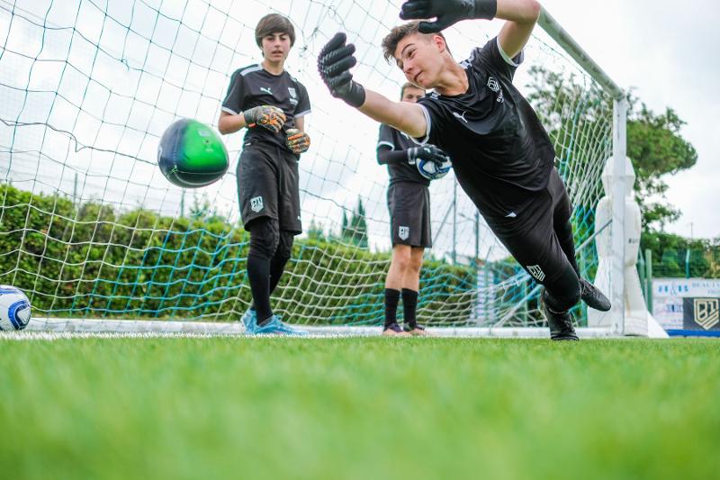 Tre aspiranti portieri del campus estivo calcio si allenano intensamente a turno