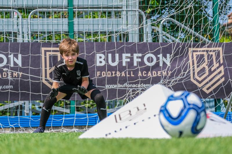 Un giovanissimo portiere del campus estivo calcio allena i suoi riflessi attraverso una piramide che causa improvvise deviazioni quando viene colpita dal pallone
