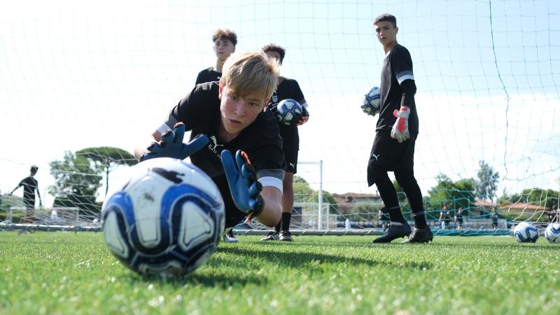 Quattro aspiranti portieri si allenano nelle parate in tuffo al campus estivo calcio