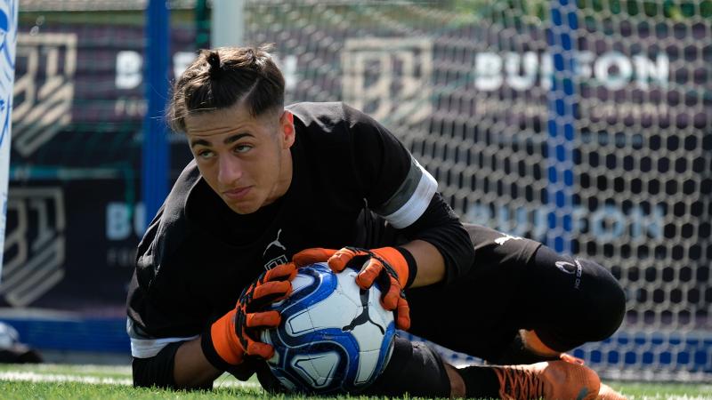 Un portiere del campus estivo calcio ha appena bloccato un pallone e si sta per rialzare