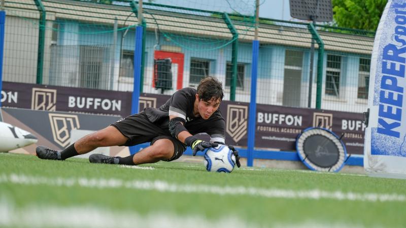 Con una parata acrobatica, un portiere del campus estivo calcio blocca un tiro basso 