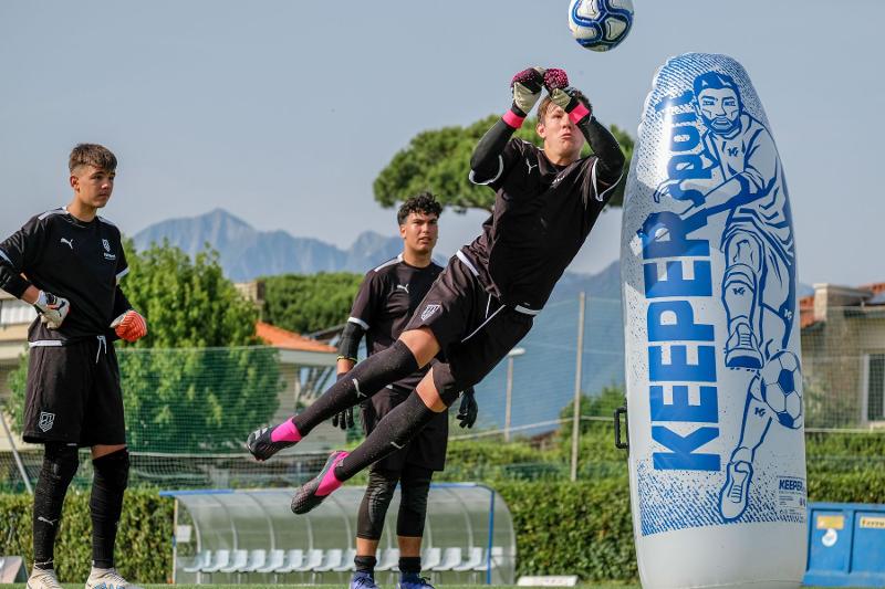 Un portiere del campus estivo calcio si tuffa in volo per parare un pallone con i pugni