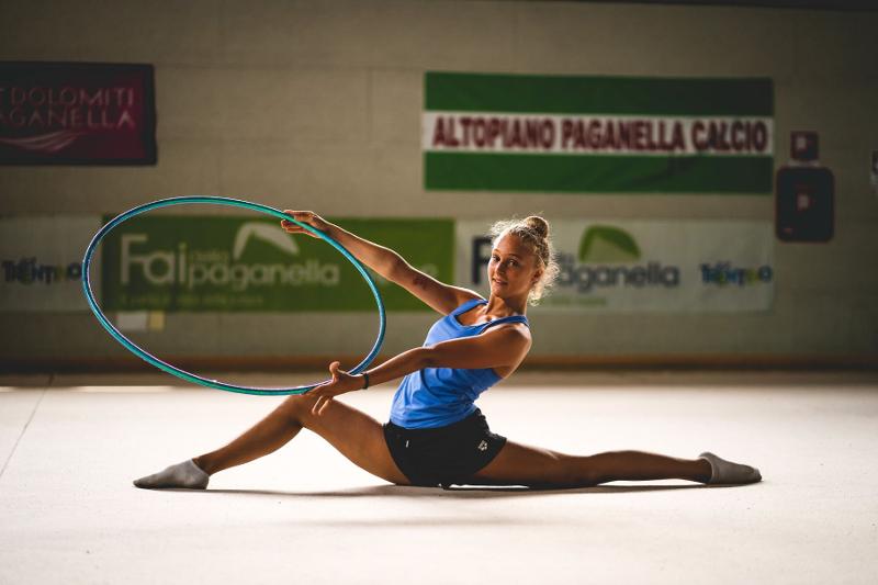 Una ragazza del campo estivo ginastica ritmica esegue una perfetta spaccata reggendo un cerchio con entrambe le mani