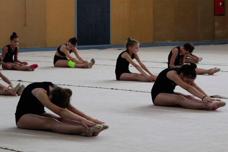 Alcune ragazze del campo estivo ginnastica ritmica fanno allungamento prima di iniziare l'allenamento in palestra