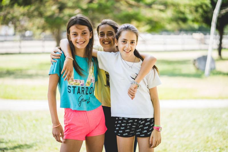 Tre ragazze del campo estivo ginnastica ritmica si abbracciano con il sorriso in faccia in un parco