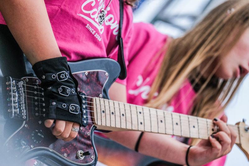 Una ragazza suona la chitarra al campo estivo musicale