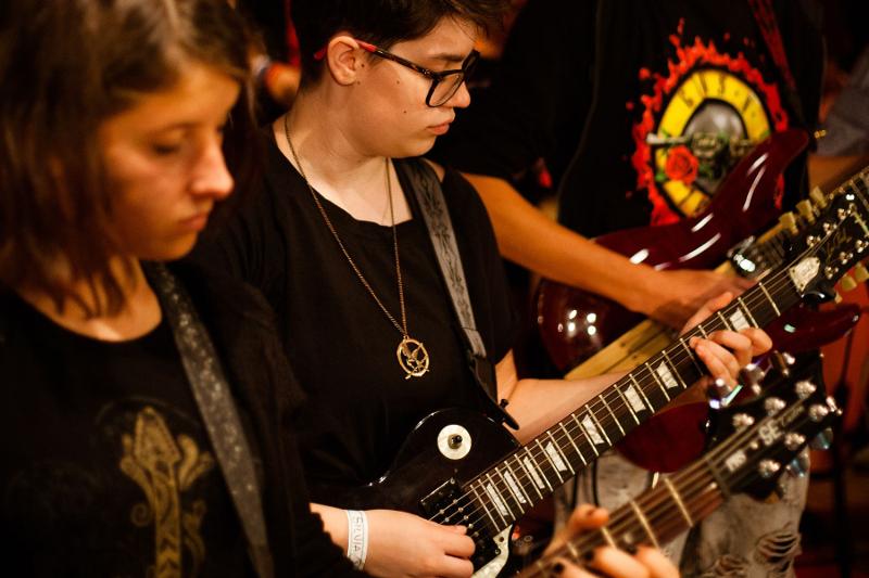 Un partecipante del campo estivo musicale si concentra mentre suona la chitarra