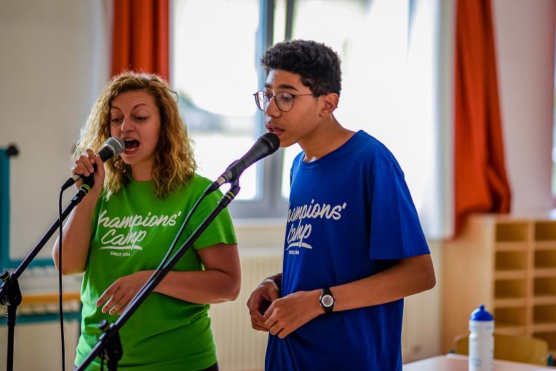 Al campo estivo musicale un ragazzo e una maestra esercitano la voce insieme al microfono