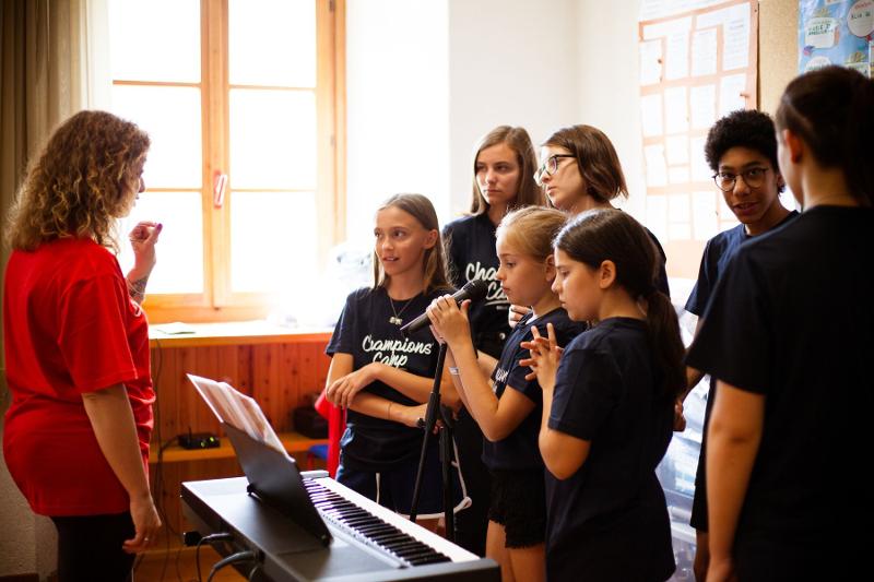 Un maestro aiuta un ragazzo con gli spartiti del pianoforte al campo estivo musicale