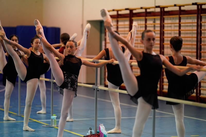 Al campo estivo danza, delle ragazze fanno riscaldamento sollevando la gamba in aria prima di fare danza classica