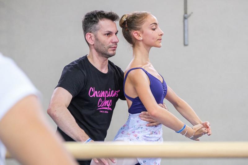 Un'istruttore aggiusta la posa di una ballerina al campo estivo danza