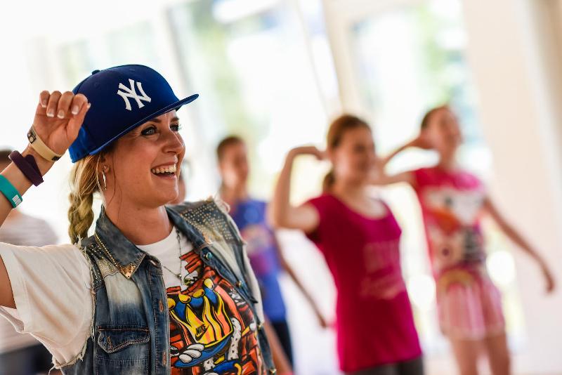 Una ragazza con il cappellino hip hop sorride mentre esegue una coreografia al campo estivo danza