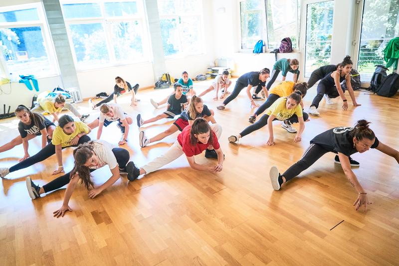 Il gruppo fa stretching di gruppo prima dell'allenamento al campo estivo danza mare