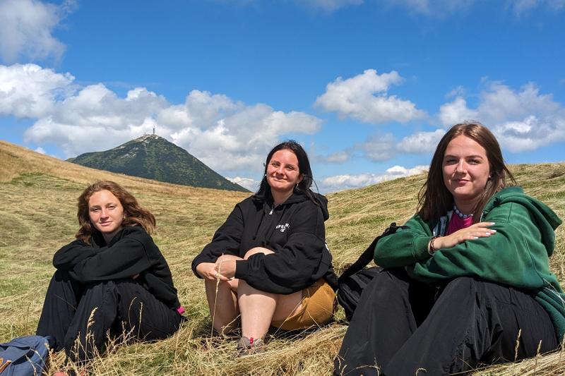 Tre ragazze del campo estivo crescita personale scattano una foto sedute su un prato di montagna con gli Appennini sullo sfondo