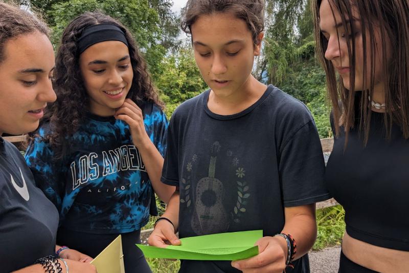 Quattro ragazze leggono una lettera durante un'attività ludica del campo estivo crescita personale