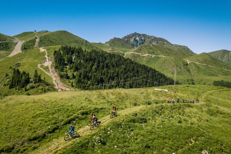 Ai viaggi organizzati Trento tre ragazzi fa una gita in bicicletta con delle montagne verdi sullo sfondo
