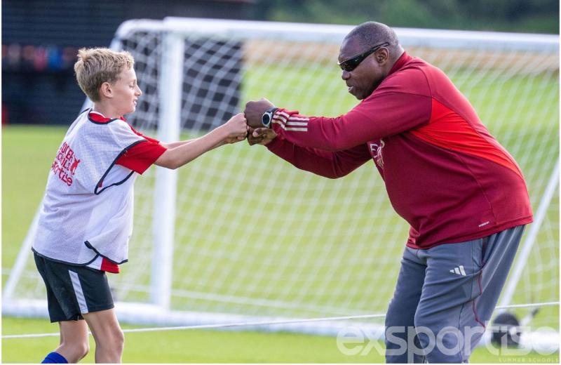 Un coach supporta un giovane talento al campo estivo calcio Inghilterra