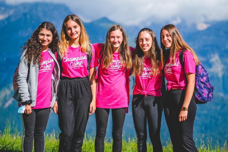 Cinque ragazze del campo estivo calcio sorridono davanti alle montagne per una foto di gruppo