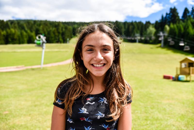 Una ragazza del campo estivo calcio ride sulle distese di prati in montagna