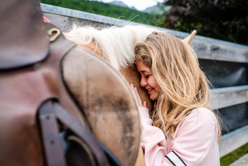 Al campo estivo equitazione una ragazza abbraccia un cavallo sorridendo
