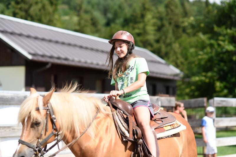 Al campo estivo equitazione una ragazza passeggia a cavallo con un elmetto in testa