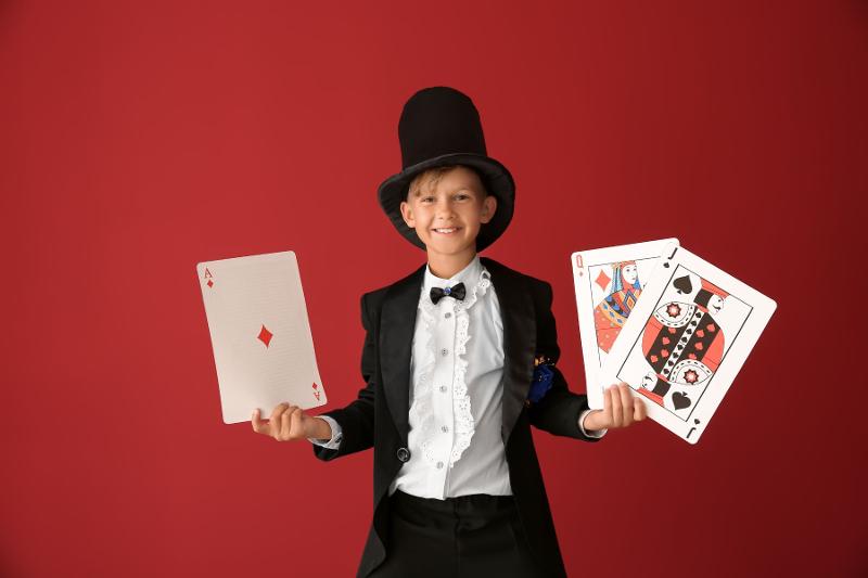 Un partecipante del campo estivo magia vestito con un costume da mago illusionista regge delle grandi carte in mano