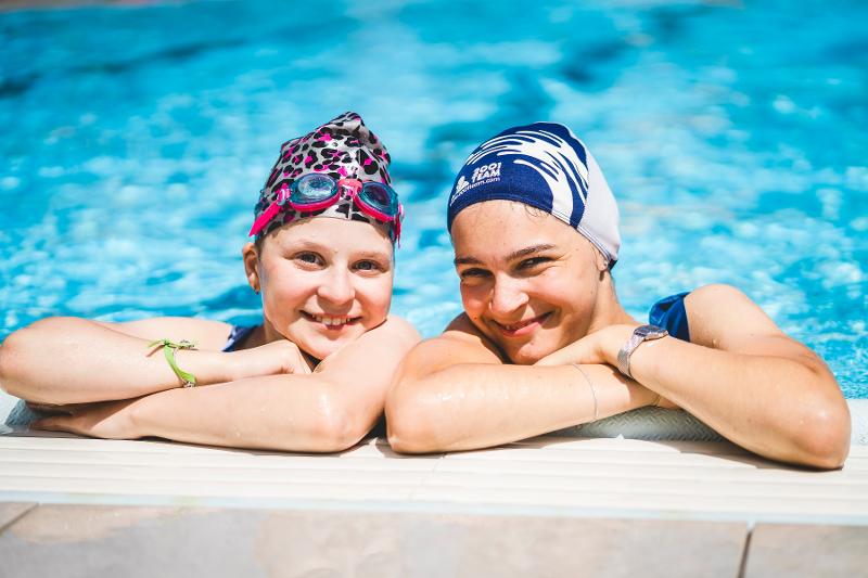 Due ragazze del campo estivo magia sono appoggiate a bordo piscina 